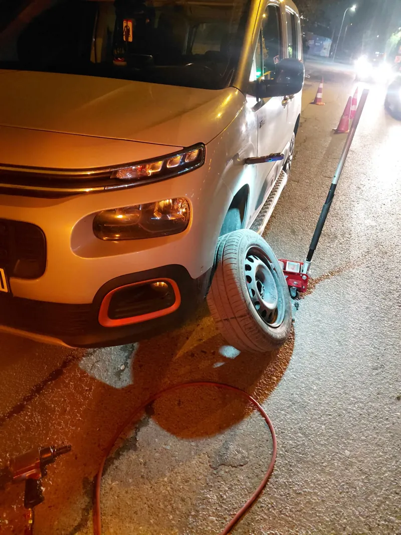 Gece yol kenarında kriko ile kaldırılmış otomobil