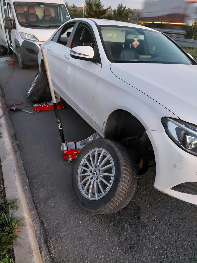 Yol kenarında kriko ile kaldırılmış otomobilin sökülen tekerleği